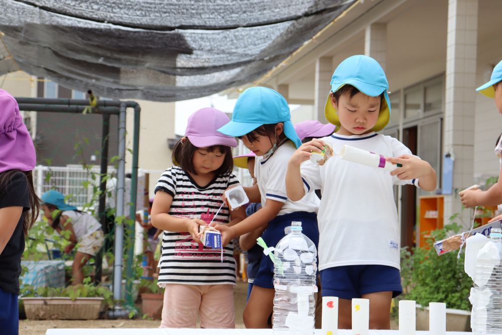 雨の日が続く・・　梅雨
室内遊びが多い日が続きましたが、中遊びで夢中になって遊んでいた　“鉄砲”
それを使って、友達と楽しく遊ぶことはできないか・・　考えました



最初は・・
的は紙１枚でしたが・・　改良を重ね・・　立体的な的に変身♪
鉄砲も、自分たちがすると飛ぶが・・　小さい友達には難しい様子

「ここ、持ってみて！」