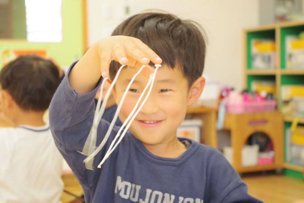 《４歳児》
ゾウ組さんは５種類のきのこを観察しました。
えのき、しめじ、しいたけ、エリンギ、まいたけ、と順番に見せていき、
「これは何ていう名前か知ってるかな？」と聞いてみると、エリンギの時に、
「まつたけ！！」との声が。まつたけを知っていることにもビックリ＆感心しました♡

きのこを触って観察しているとき、
「えのきの頭、何かねちょねちょしとる」と気づいた子がいました。
何となく指につけてみると・・・なんと、くっついています！
ぱぁっと笑顔になり、すぐ隣の友達に伝えます。その子も真似して、また隣の子に・・・と、どんどん広がり、みんなで『えのきを何本つけれるか』の遊びに発展しました。
子ども達は『楽しいこと』に気づく天才ですね♪