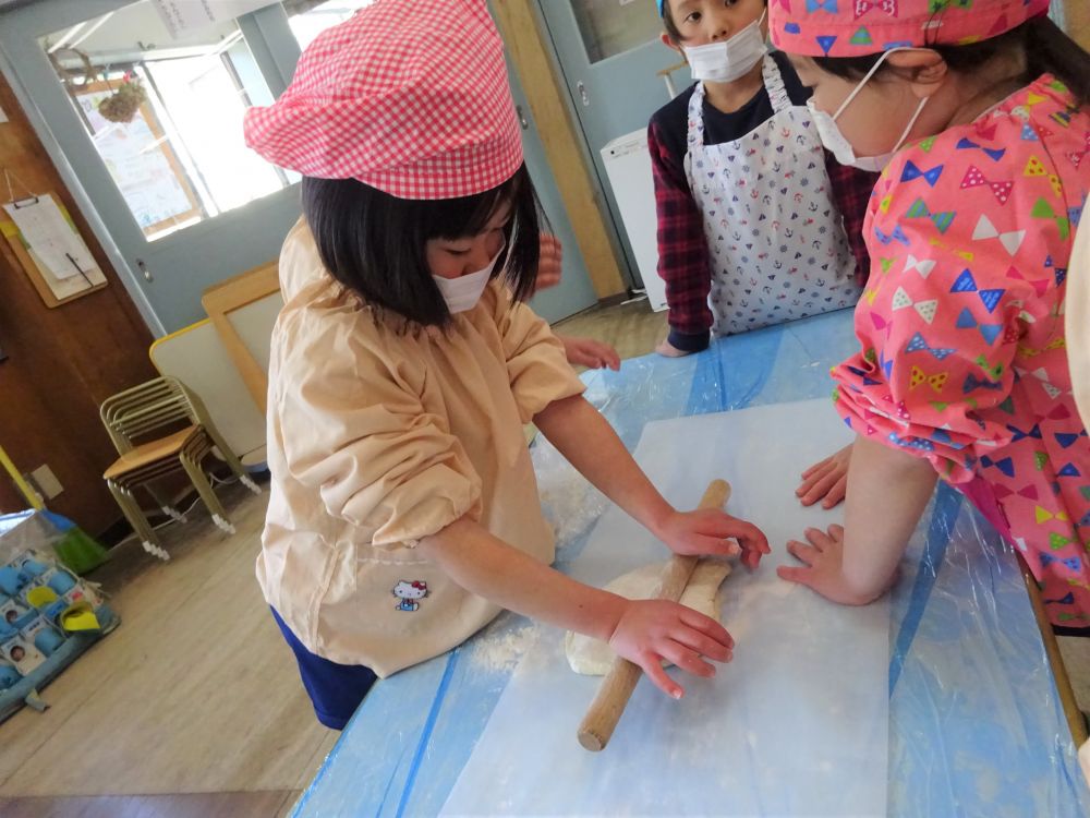 生地がまとまってきたので今度はお楽しみのふみふみタイムです♪
ビニールの上からみんなでふみふみしますが、Ａくんが

｢裸足じゃけー気持ちいいよ！｣
｢いいなーでも靴下履いても分かるーぐにゅぐにゅして気持ちいーね｣

本当ですね！素足だとうどんの生地の感覚が敏感に感じることが出来ますね。
ご家庭でするときは是非みんな裸足でしてみて下さい！

みんな楽しくふみふみした後は麺棒で伸ばしていきます。

｢こっち持っとくよ！｣
結構力がいりますのでみんな一生懸命力を入れて伸ばしていきます！

頑張れ頑張れ！！！
