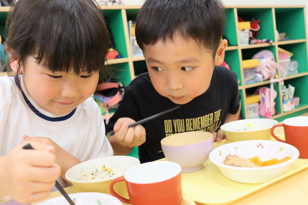 今日は七夕☆彡
園庭では、子ども達の願い事を書いた短冊や笹飾りが風に揺れていました。
あいにくのお天気で、夜に天の川は見られないかもしれないけれど・・・給食では天の川に見たてた【七夕そうめん汁】が登場しましたよ♪

食べる前に、配膳された給食を見て、
「やったぁ！そうめん大好き！」
「人参がお星さまになっとるね！」
嬉しそうな子ども達の声♪

中でも、昨日収穫した“オクラ”が入っていることに気づいたＨ君の笑顔はピカイチです♡
「オクラどうだった？」と聞くと、
「すごいおいしかったけぇ、一番最初に食べた！」と教えてくれました。
食べているとき、友達のそうめん汁も気になって横目でチラリ☆
“ボクの収穫したオクラ、早く食べて欲しいな・・・”と思っているのかな♡

キリン組さんが植えてから、なかなか育たなかったり、アブラムシに葉を食べられたり、と心配続きだったオクラの生長。
でもみんなの願いが届き、収穫の日を迎えられ、七夕の今日みんなで食べられたことに感謝の気持ちでいっぱいです☆彡
