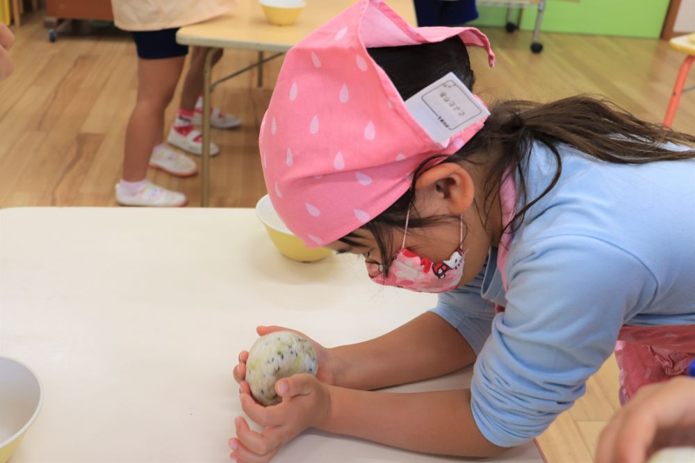 「いい匂いじゃねぇ！」
「わぁ～！たくさんある～！」
「これって何合あるん？」
子ども達の感想は様々♡
黒ごまを入れて、しっかり混ぜれば完成です！

次に一人分の分量のご飯をもらい、自分好みの形に握ります♪
丸にしたり、三角にしたり、おしり探偵の顔にしたり・・・　子ども達の発想は様々です。
ハート型にしたいRちゃんは、真剣な表情でもくもくと・・・。ハートのへこみの部分が難しいようで・・・。指でおしたり、手首を使ったり、理想の形を求めて色々と試していました♡
「考えて、やってみる。」その繰り返しです。
おにぎり一つでも、たくさんの挑戦が詰まっていますね。