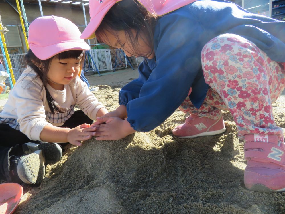 『一緒にしよう』が増えてきたクマ組さん
今日も園庭で砂山作り…


一人で作っていたⅯちゃんの所にやってきたYちゃん

『一緒に作ろう！』『いいよ！』と作り始めました

『こうやってしたら硬くなるよ！』といいながら力いっぱい砂をギュッギュっと押していきます