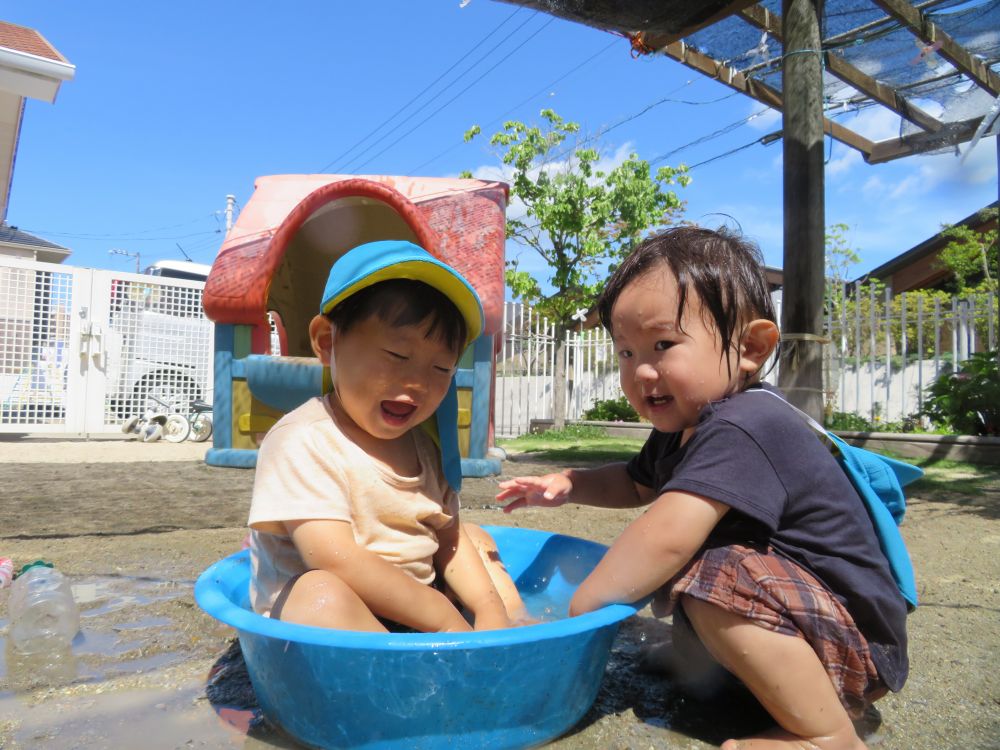 タライの水を手で叩いて遊ぶＹ君とＲ君

お互いが叩いた水しぶきが顔に散って楽しい！

楽しすぎて思わずタライに入っちゃった♡

暑さに負けず、今日も園庭には子ども達の笑い声が響いています！


