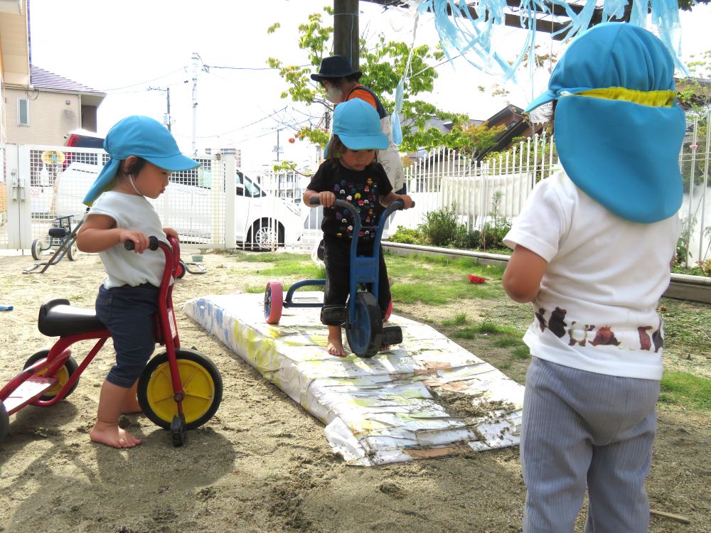 いつもは園庭をぐるりと周って遊んでいる三輪車チームですが
今日は少し難関なコースにチャレンジするようです…

最初の登りからなかなか登れず苦戦するＵちゃん…

心配そうに見守るRちゃんとIちゃん…

一生懸命、足をふんばりやっと登りきると今度は急な下り坂…

ゆっくり慎重に下って無事にクリア！