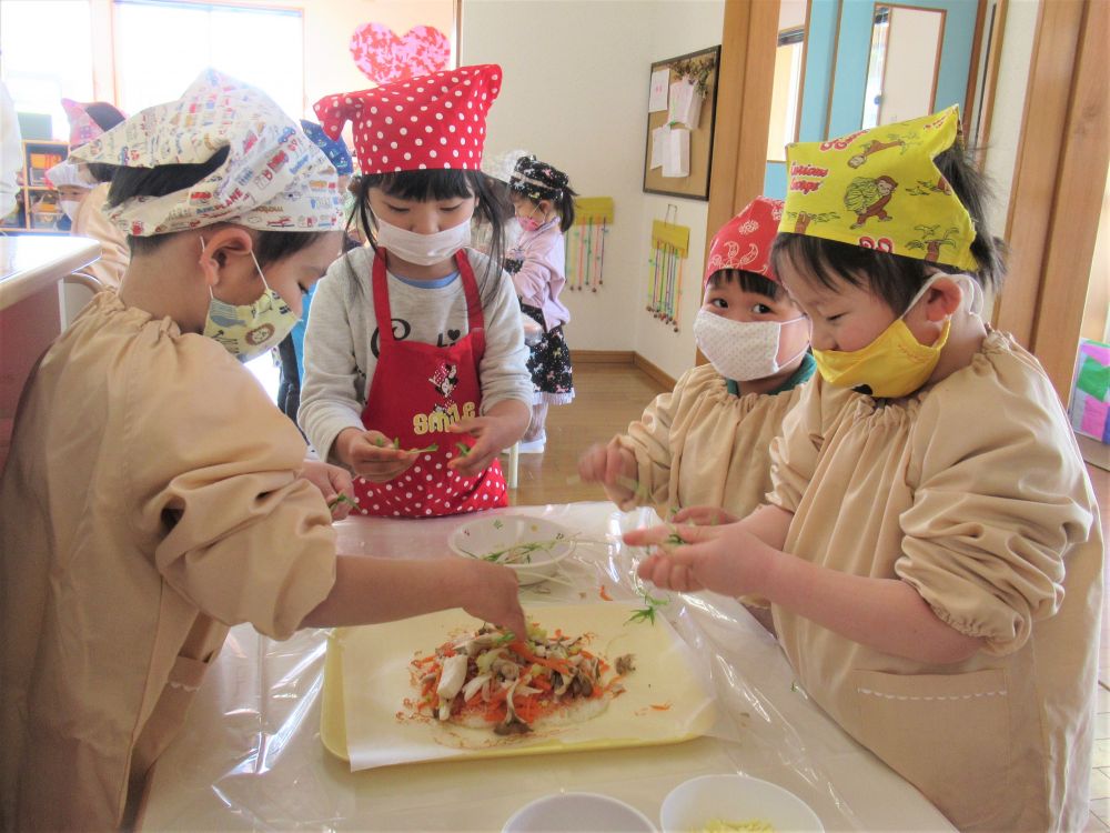 グループごとに、つぶしたご飯を合体させて・・・
次はおいしい味付け♡
スプーンを使い、ケチャップを塗っていきます。
「ここ、まだ白いよ」
「私がぬろうか？」
友達と声を掛け合う姿も見られました♪

ケチャップが塗れたら、後は具材をのせるだけ♡