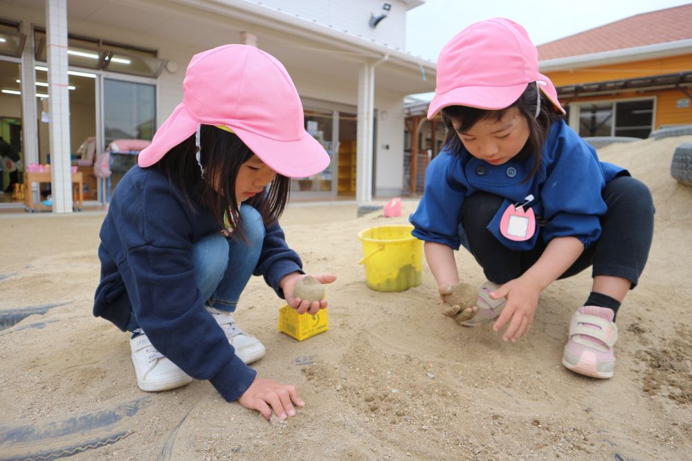 キリン組さんが泥団子を作っているのを見て・・
「わたしたちも作ろう♡」と
お気に入りの場所と砂を探して・・・

「砂をかけたらつるつるになってきた！」
「ほら、触ってみて♡」