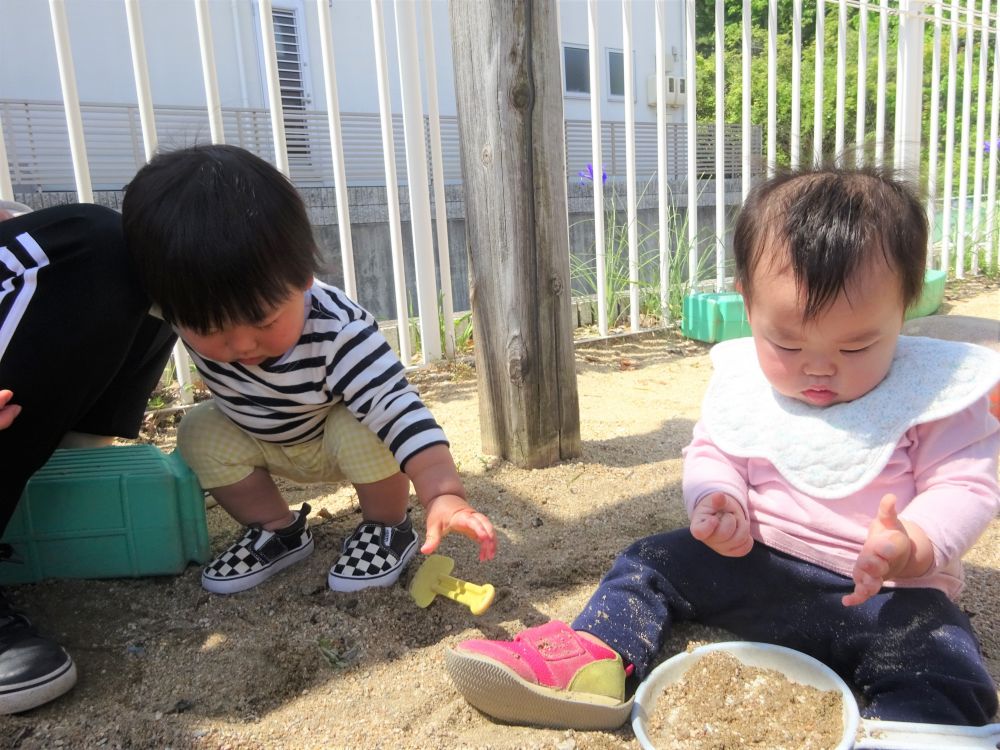 初めての園庭遊び…
砂を握っては手を広げ…
安心する先生の側で砂の落ちていく様子と感触を繰り返し楽しみました。