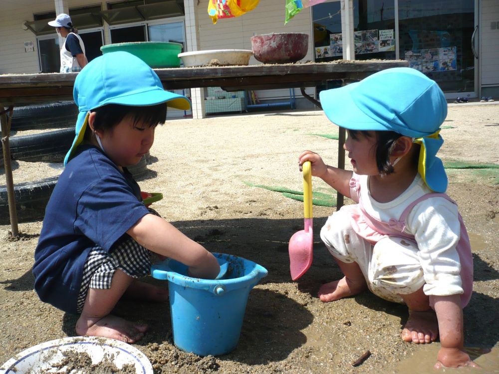 ぽかぽか陽気の中、今日はいつもと違う第三園庭に出て遊びました
子どもたちはおもしろいことを見つけるのが得意！
周りの環境に興味津々で、それぞれ好きな遊びを見つけて楽しんでいます


砂場の近くに水たまりができていました
「お水、入れる～！」
「わたしも！」
Ｈくんがスコップでバケツに水を入れていたのを見て、
Ｒちゃんが手伝います
Ｈくんは水が増えて嬉しくて、RちゃんもHくんが喜んでくれたので、
二人は目を合わせて微笑み、心を通わせていました