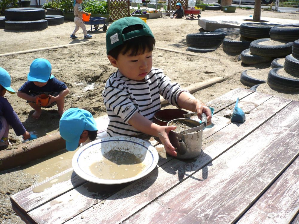 「味噌汁だよ！」
Rくんは砂と水をぐるぐる混ぜてどろどろに‥
子どもたちは色々なものに見立てて遊んでいます