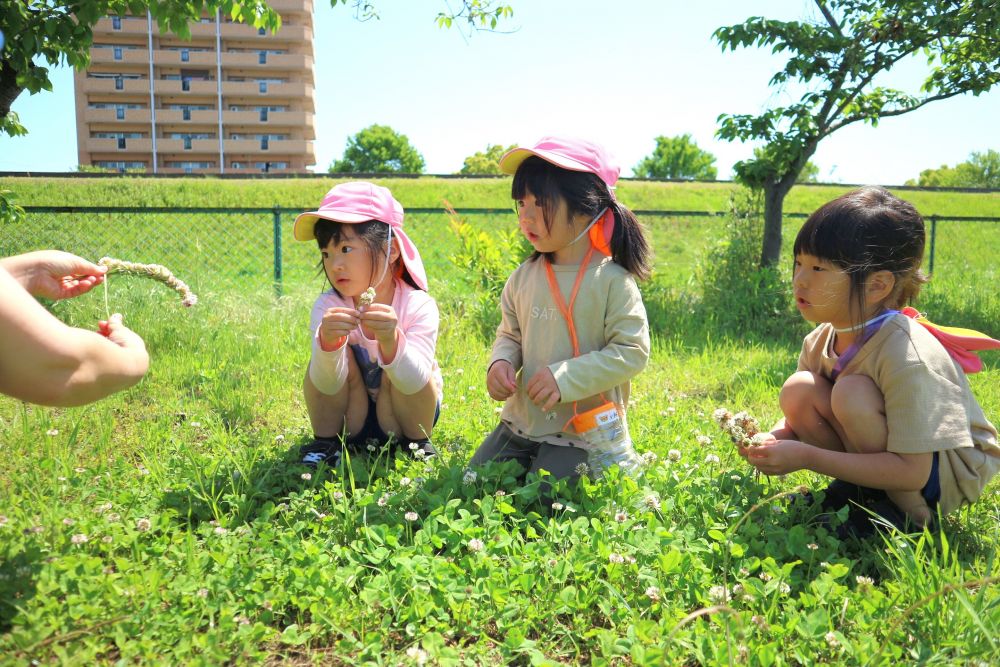 一人一人好きな遊びを楽しんだり
興味を持ったことをしてみたり・・・


草花を使った遊び♡
”シロツメクサで冠できる”ことを知り
「やってみたい！！」と
保育教諭がしている姿をじっくり見る・・

保育教諭と一緒にやってみたり、
聞いたこと・見たことをもとに自分なりにやってみたり・・