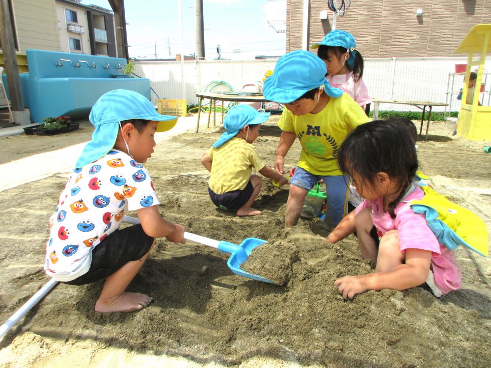 だんだんと暑さが増してくるこの季節
ひんやりとした砂や水の感触が気持ち良く感じられます♡
クマ組の子どもたちも砂や水に触れることを喜んで、感触を味わいながら遊んでいます



「Kくん、かけてよ～」
「いいよ！」
「Iくんもするよ！」

スコップやシャベルでエッサ！ホイッサ！
みるみるUちゃんの足元は砂山に
Uちゃんは満足したかと思いきや・・・
「もっともっと！」
Uちゃんの思いに応え、周りの友達は一生懸命砂を集めます！