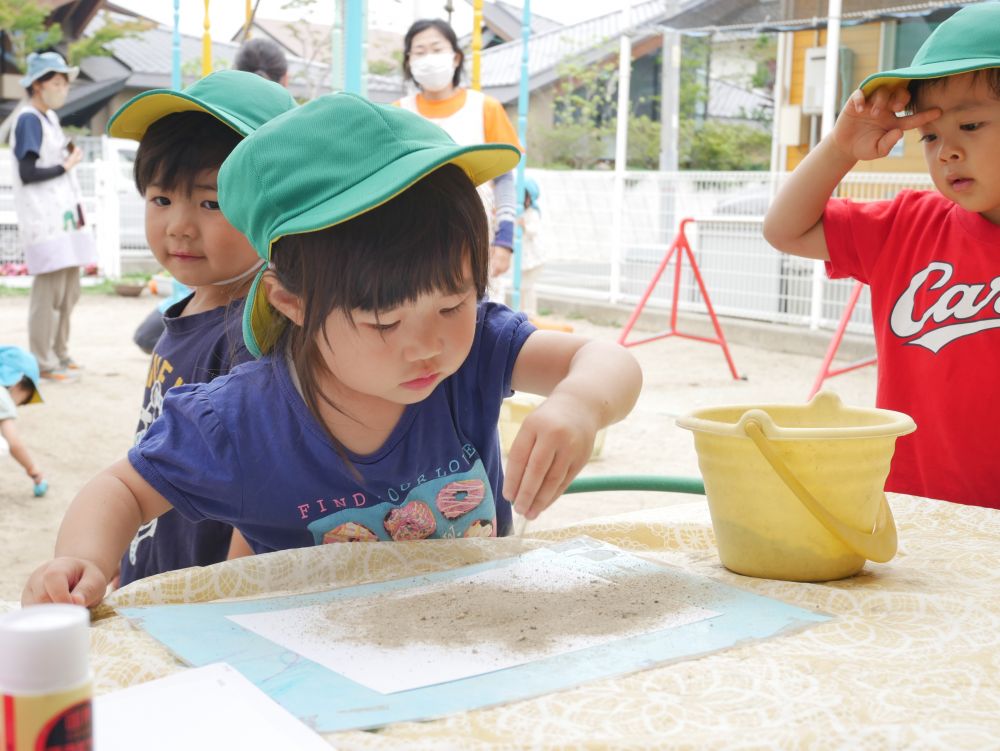 砂の感触って面白い！！
さらさら～
ざらざら～
ぱらぱら～
色々な音がする♡ついつい夢中になる子どもたち


今日は砂を使って砂絵を描いてみることに
のりで紙に模様を描いて・・・
上から砂をかけるとどうなるのかな？
『いっぱいかけるぞ～』
繰り返し砂をかけるⅯちゃん
