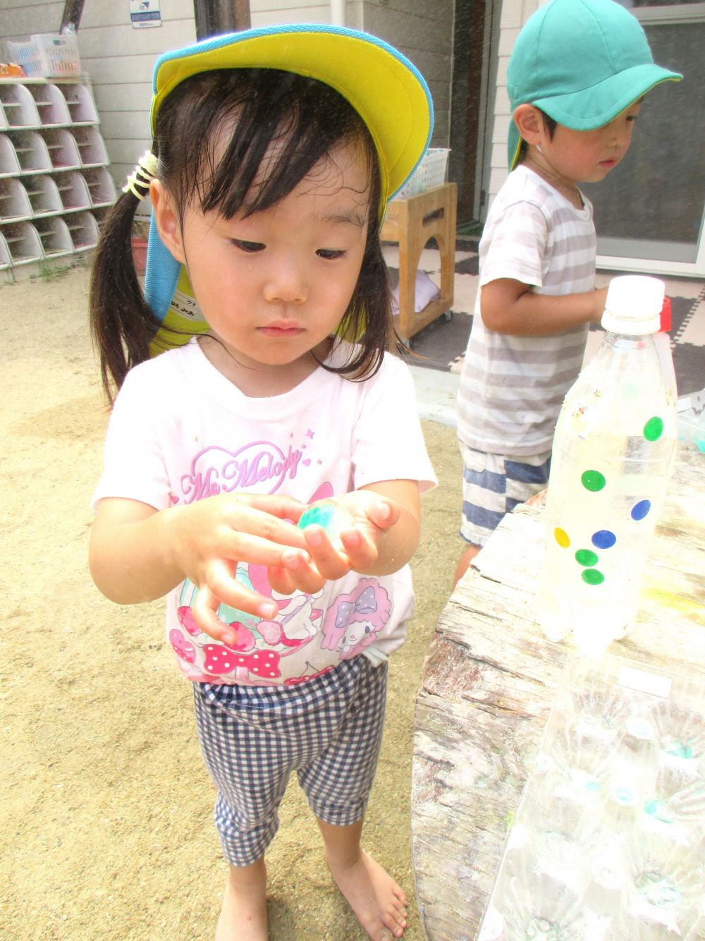 夏本番の暑さの中でも
涼しく過ごせる工夫をしています♪
その一つが氷遊びです！
食紅で色を付けた氷に興味津々です

「わっ、冷たい！
　気持ちいい・・・♡」
さっきまで日向で水鉄砲で遊んでいたⅯちゃん
気持ち良さそうに冷たい氷を握っています
