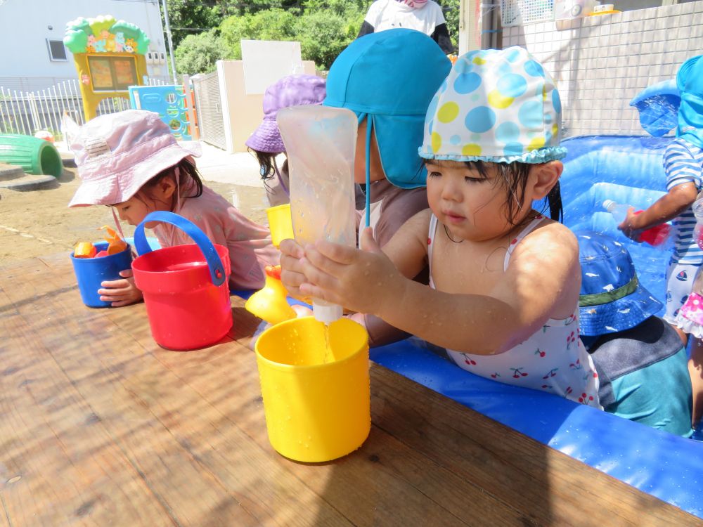 ケチャップのケースからカップに水くみ中のMちゃん。
水を入れるのは・・・難しい。
先生やお姉ちゃんに手伝ってもらいながら、何度も繰り返してカップにいっぱいのお水を入れることが出来ました。

最後まで諦めずに頑張ったよ！