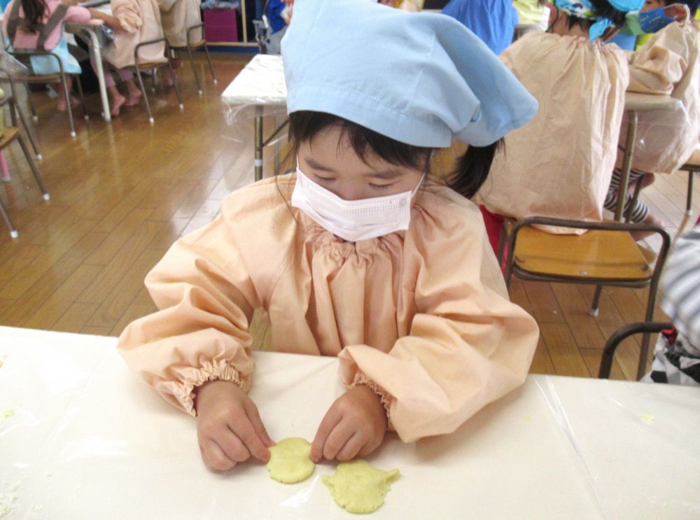 その後は、いよいよレモンクッキー作り。
材料をすべて混ぜ、しっかりこねて、生地作りを頑張ります。
お椀の中で、指の力を使い、さらさらの粉から一つの生地へ・・・。
「ほんとに先生みたいに丸くなる？」
「くっつかんけど～」と、
中々まとまらなくて四苦八苦。でもみんな真剣な表情でコネコネしてくれました。

生地ができたらレモンの形に成型です♡
左右をとがらせるのがポイントなのですが・・・
「ここをこうしてピュッと・・・できた！」
「カレーパンマンみたい♪」と、レモンの形ができると嬉しそうな声が聞こえてきます。