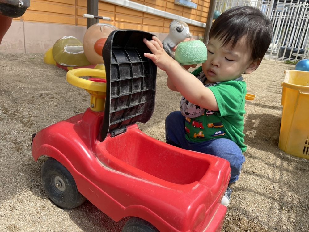 車の蓋をあけておもちゃを入れようとするＫくん
手を離すと蓋が閉まってしまう・・・
