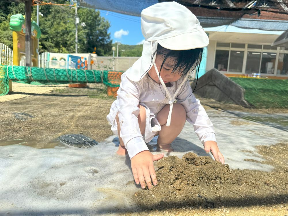 こちらでは、砂遊びが好きなTちゃんが
水遊びで濡れた園庭の泥を
手で寄せて、山を作っています！👐！

さらさらの砂とまた違った感触を楽しんでいるようです♪