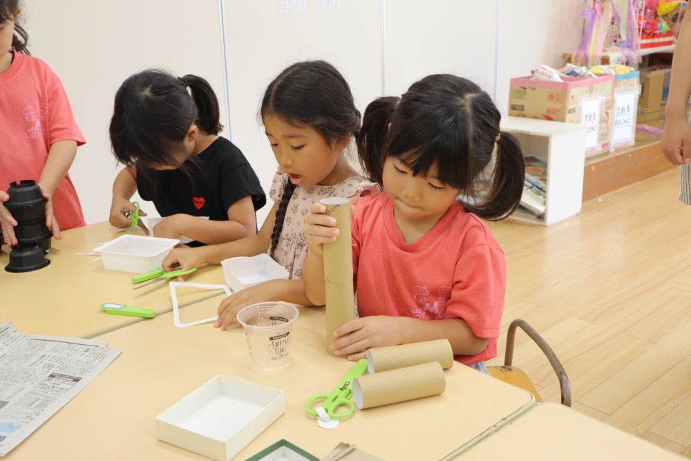 今年のキリン組さんの競技名は”はこにむかってボーン！”

ルールは簡単！
タワーの上にあるボールを先にゲットしたチームの勝ち♪
しかし、タワーの周りの円の中には入れません
入れないということは手足は使えません
ボールが取れるようなアイテム作りが必要になります！

ルールを聞いて、早速アイテム作りに取りかかります！
空き箱・ダンボール・ペットボトル・牛乳パック・トイレットペーパーの芯・ラップの芯・カップ・トレー・・・
自由に使える廃材の中から、「これだ！！」と思うものを手に取り、形にしていきます

