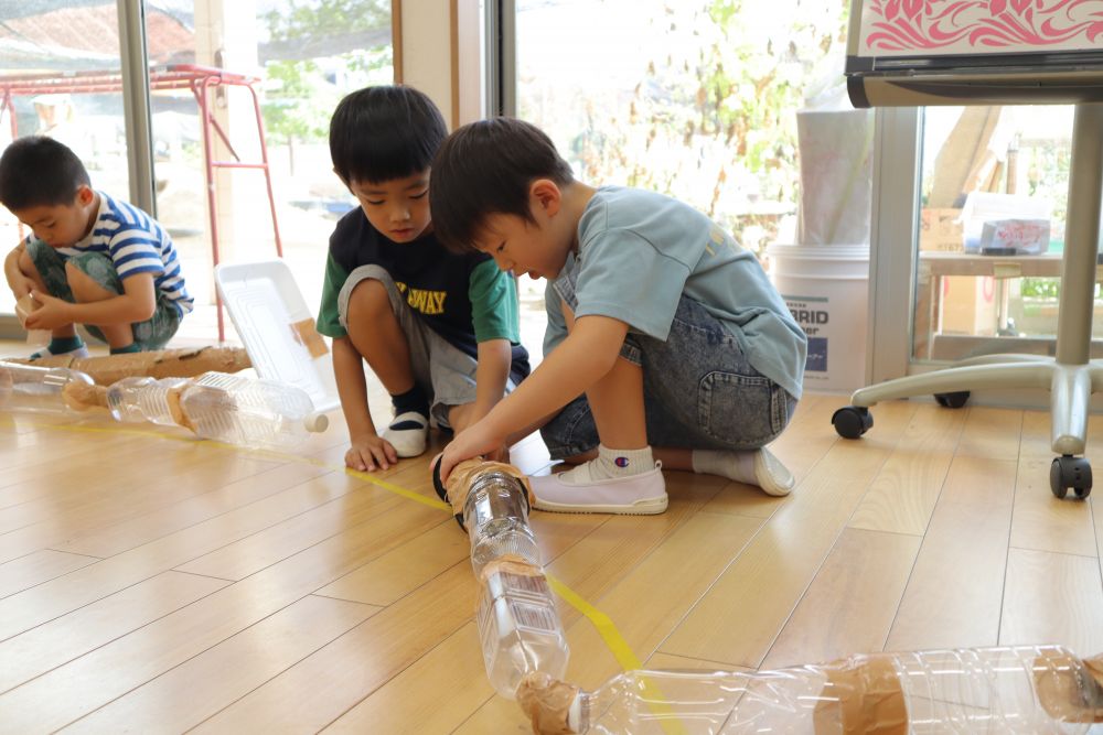 子どもたちはよく考えました
なので先生たちも考えました
「もっと面白く・・・！」

ということで、ちょっとだけルール変更♪
円をすこ～し大きく
ボールは箱に変わり、1チーム13個用意しました
相手チームの箱を積み上げ、多くゲットしたチームの勝ち！

条件が変わったのでアイテムの手直しをして・・・
さあ、やってみよう！