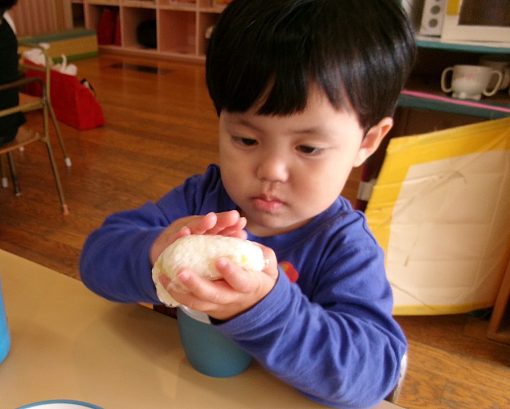 今日の給食は秋の味覚「さつまいも」を使ったさつまいもご飯でした。

門田保育園とゆめはうすのお兄さんお姉さんが稲刈りしたお米を少しおすそ分けしてもらい、
先日クマ組さんが掘ったあいはうすの畑でできたさつまいもと一緒に炊きました。

そして、クマ組さんはミニクッキング！
さつまいもご飯をおにぎりにして食べました。

ラップで包んだご飯をぎゅっと握って、思い思いの形のおにぎりにします。