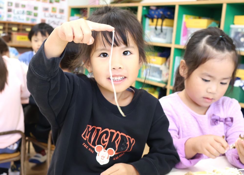 ３歳児さんは４種類のきのこ（えのきたけ・しめじ・エリンギ・まいたけ）と触れあいました。
４・５歳児さんは４種類のきのこに加え、４種類のいも（さつまいも・里芋・山芋・じゃがいも）と触れあいました。

一番人気は“えのき”
小さな“かさ”の部分が、少しねとっとしていて、指や肌にくっつくのが面白い♡
「みてみてー！」と指にくっついたえのきを見せてくれます。
他のきのこで試すも失敗・・。
「なんでこれだけくっつくんかなぁ？」と不思議でたまりません。
夢中になって観察していました♪