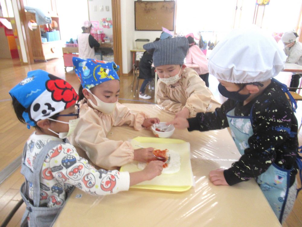 まずは、土台となる生地作りから。
ラップに包んだご飯をつぶして、もちもち食感が出るようにします♪
指でもみもみしたり、上から押したり、どうしたら上手くつぶせるか、自分たちで考えます。
「あ、ごはん、ちょっとあったかいね!」
「むにむにして面白~い♡」
と、感じたことを伝え合います。
「つぶつぶがなくなるほうがいいの?」と、Yくん。
「しっかりつぶしたほうが、もちもちした食感になるよ」と伝えると、
指先を使い、ご飯粒をひとつひとつ押していました。