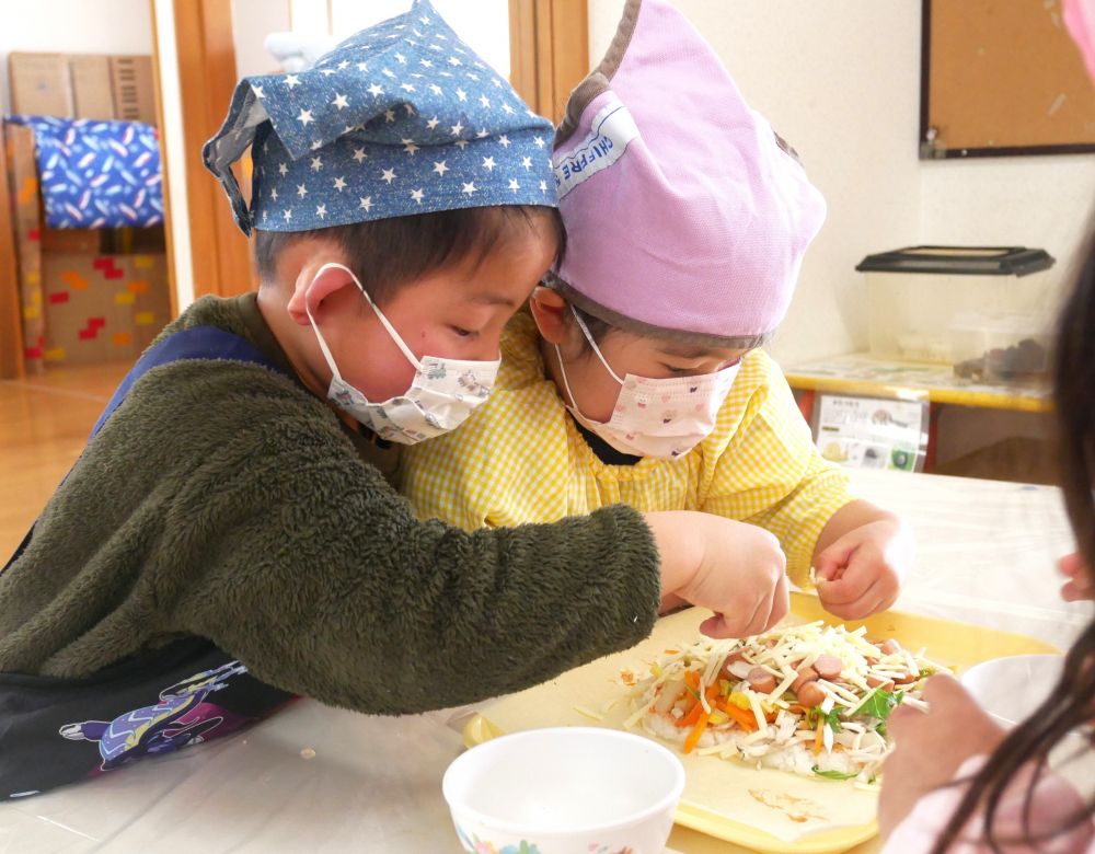 「ここ、具が少ないかね?」
「こっちから人参持ってくる?」
と、ご飯全体に具材がのるよう、友だちと相談しながら楽しむ子ども達。
白菜・人参・ウィンナーなど、その他の具材も残さずトッピングし、最後にチーズを散らして、彩りキレイに完成です♡