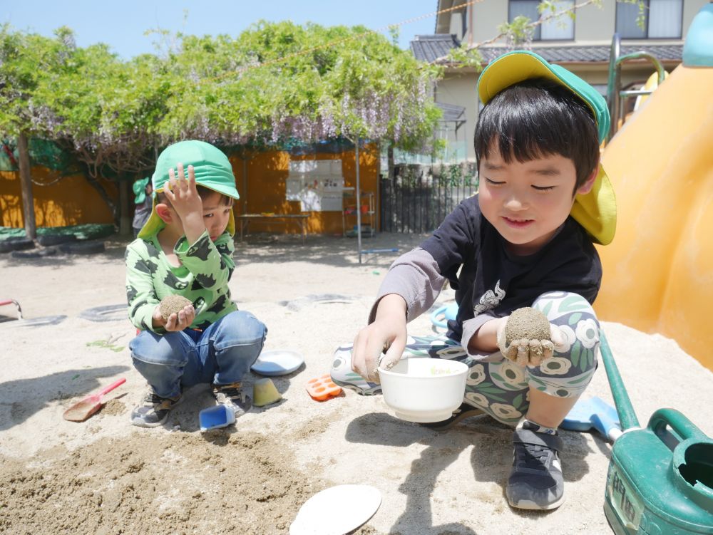 協力して作ったり、自分の団子を見せ合ったり
小さいのや大きいのを作ったり…
友達と意見を出し合いながら楽しむ
朝の会で女の子が泥団子を作ったよ!!と発表
友達が作るの難しいもん…と言うと
どうやって作ったかを教えてくれました
すると…やってみたくなったのかな?
男の子たちもどんどん挑戦♪
「みてー、皿粉も作ったよ」とYくん