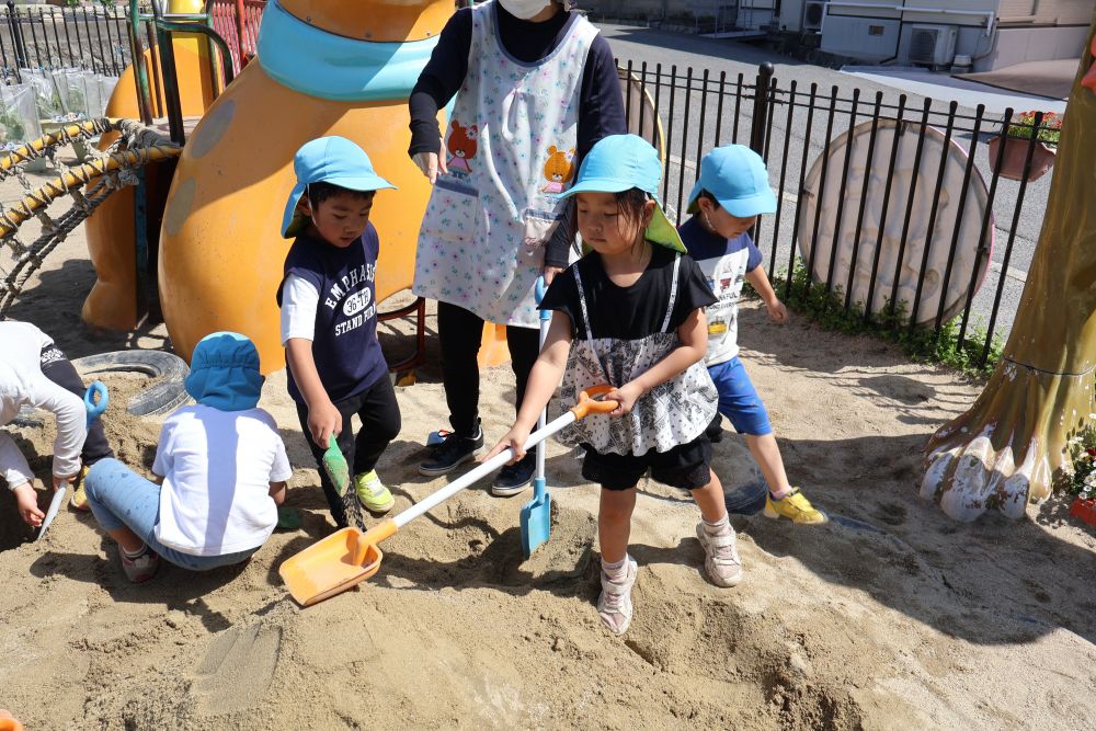 「 大きいお山が作りたい‼ 」
各々スコップを持って来てどんどん大きな山に…
崩れても何度もチャレンジ♪
「 どうやったら壊れんかな? 」
「 大きいのどうやって作るん? 」
疑問を抱き、先生にヒントをもらいながら
子ども同士で声を掛け合い
大きな山を作っていきます
「 上手にできるけ見よって 」
と教えてあげるRちゃん