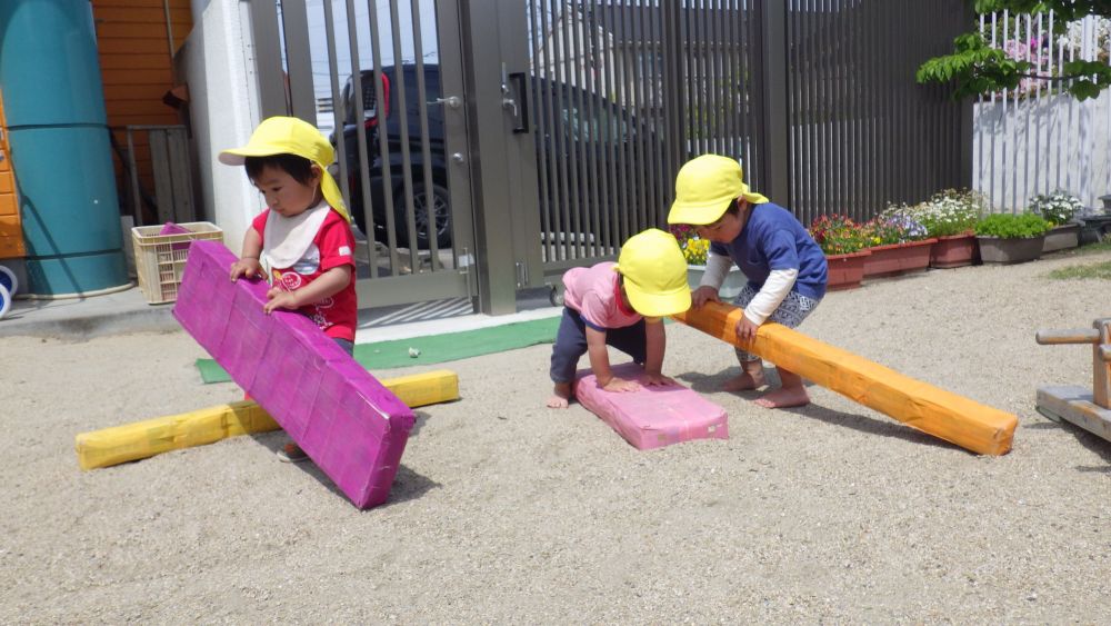 遊びを見つけるのはいつも子ども達!
牛乳パックの平均台で遊びは広がっています
キレイに並べて置いておいた平均台を崩し始めるヒヨコ組さん…
話しあう訳でもないのにお互いの考えが分かっているかのように一人一つずつ持ち運び、繋げていきます
キレイに並べられたコースでは物足りない!と言わんばかりに
少しアンバランスでスリルのあるコースを作り上げました