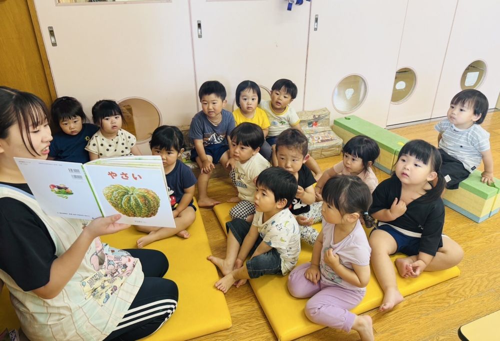 2歳児
　「やさい」

今月は、野菜を育てているクマ組さんにぴったりの絵本。

　「この野菜なーんだ？」と聞くと・・・
　「トマト！」　「キャベツ！」　「ダイコン！」
とすぐに答えるクマ組さん。
みんな野菜の名前をよく知っています！！

　「みんなが植えたオクラとゴーヤとピーマンも早く大きくなったらいいね！」
収穫を今か今かとみんな楽しみにしています♪
