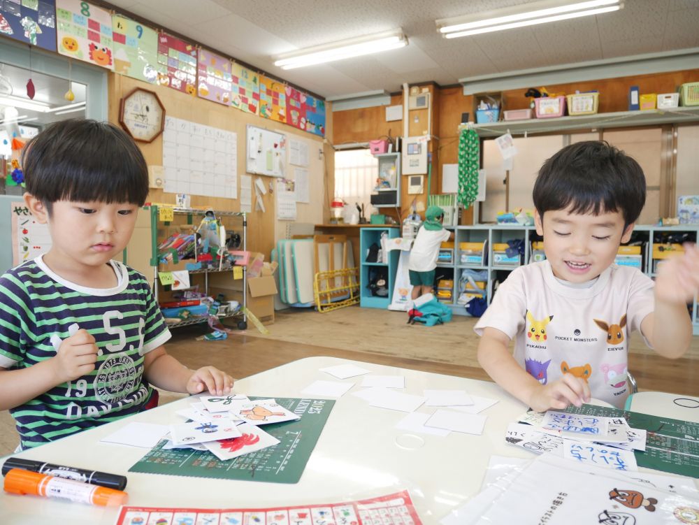 自分たちで考えたものを形にする過程で
考える力や工夫する力が育まれる…
完成した作品で遊ぶ事でさらに楽しく愛着がわく
あいうえお表を見ながら文字と絵を描く二人
会話を聞いているとかるたを作っていました
二人で文字と絵を手分けして…