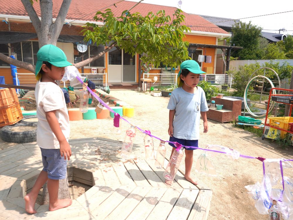 全部ひもに付けたら外にかけに行こう！
「どこにつける？」
「木からあさがおの棒は？」
「長さが足りん・・・」

紐の長さが何回しても足りなかったり…
こぶ結びしてしまってとれなくなったり…
運んでいるときにテープがひっついてグチャグチャになったり…
たくさん苦戦しながら何回もやり直しました！！