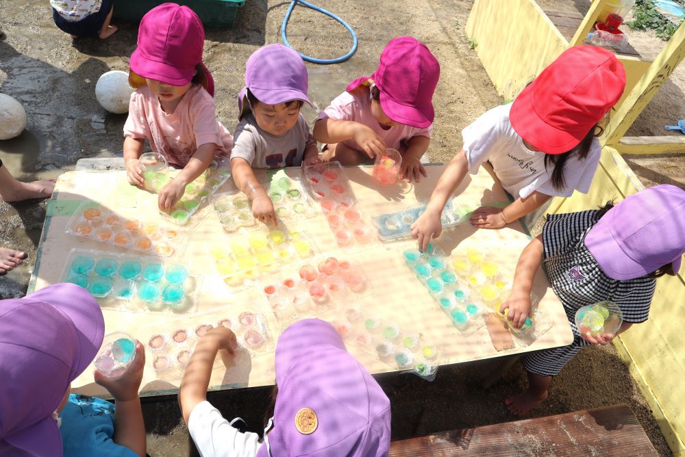 キレイな色の氷を用意♡
かわいい!触りたい!
すぐにワクワクいっぱいの目に変わり、氷に手を伸ばします!
赤・ピンク・オレンジ・黄・緑・青・・・
太陽に照らされてキラキラする氷
両手で掴んで「冷たい~っ!」と手を離す
氷の冷たさ、ツルツルした触り心地
「気持ちいい♡」触れただけで思わず笑顔になる心地よさです!