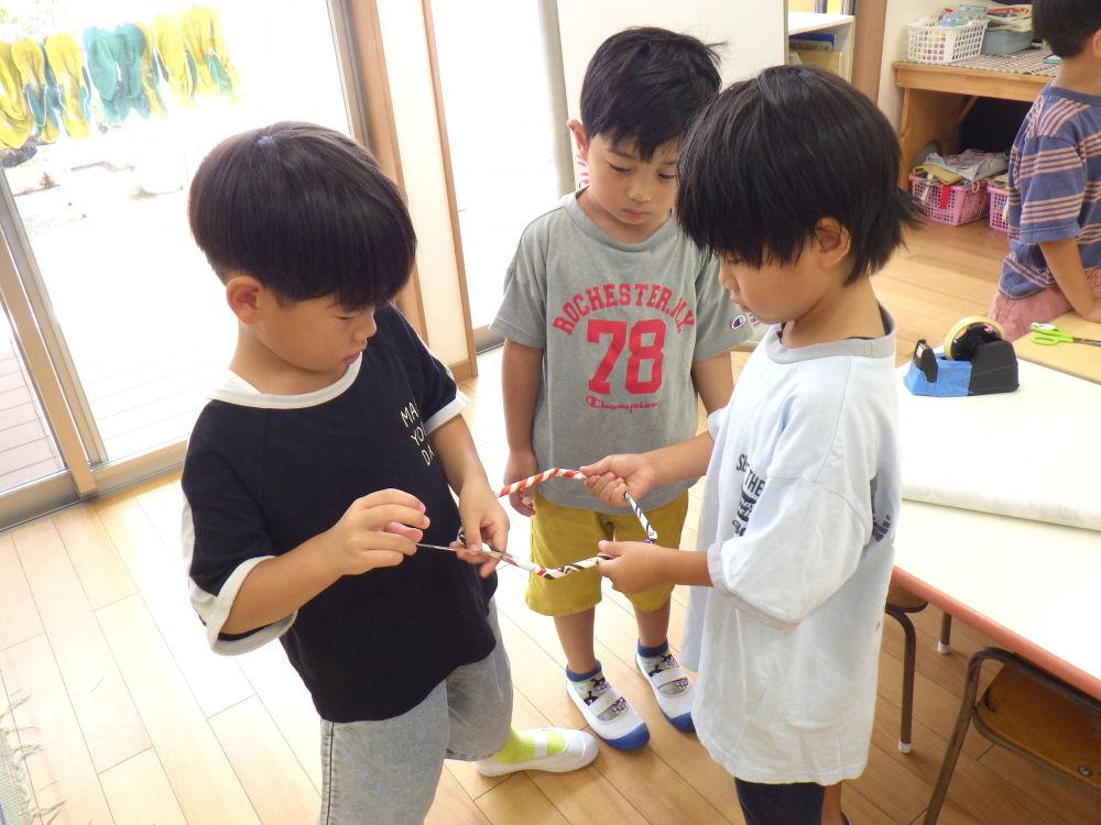 「網の所に針金みたいなのあるよね?」
「針金はないけど折れんように固くしたらいんじゃない?」
「広告で棒作って丸くしてみよ!」