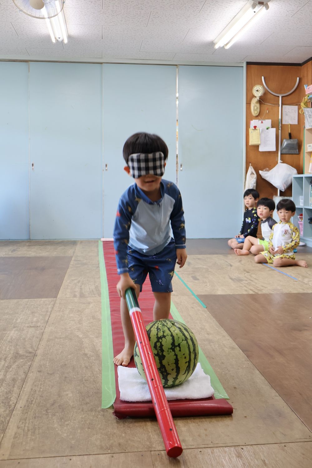 続いてHくん、片手で挑戦です☆
しかし、真ん中に当てるのは少し難しい様子
そんなとき…
友達が声をかけて教えてくれます
「後ろさがって!」
「もうちょっとボックス側よ!」
ゾウ組さんの部屋の中は楽しそうな声でいっぱい
スイカ割りをする子も、見ている子も
みんな楽しそうでした♡
さあ、スイカは割れるのか…