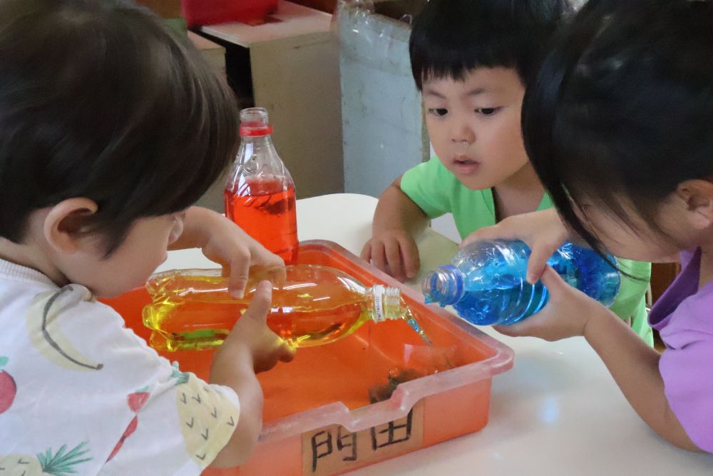 色水遊びでいろんな色を作って遊んでいるリス組さん!
でもまだ時々色の名前が迷子になることも・・・なので!
今日はみんなで『色水実験ごっこ』をしました~。
テーブルの上の赤・黄色・青を使って
先生の作った色水と同じ色づくりに挑戦☆
何色同士を混ぜたら作りたい色ができるかな?
友達と相談しながらレッツまぜまぜ~☆