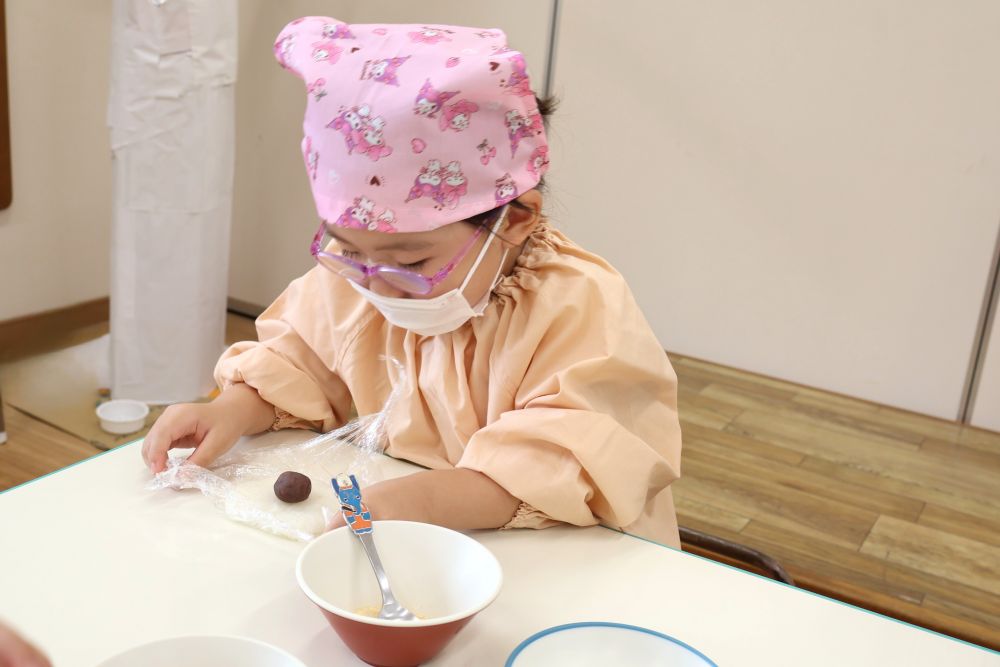 ご飯をつぶして広げたら、真ん中に丸めたあんこをおいて・・・
ちょっと技のいる、少し難しい“ご飯であんこを包む”という作業。
「ご飯からあんこがはみでる~」
「ちょっとあんこ見えるけど・・・ま、いっか♪」と、あんこに苦戦しながらも楽しそうでした。
上手にあんこを包めた子も、少しあんこがのぞいてる子も、最後にはみんなきれいな丸い形になりました♡
「園庭で泥だんご作ってるもん!」と、ゾウ組さん。
日々の遊びや経験の中で、クッキングの技も磨けています☆