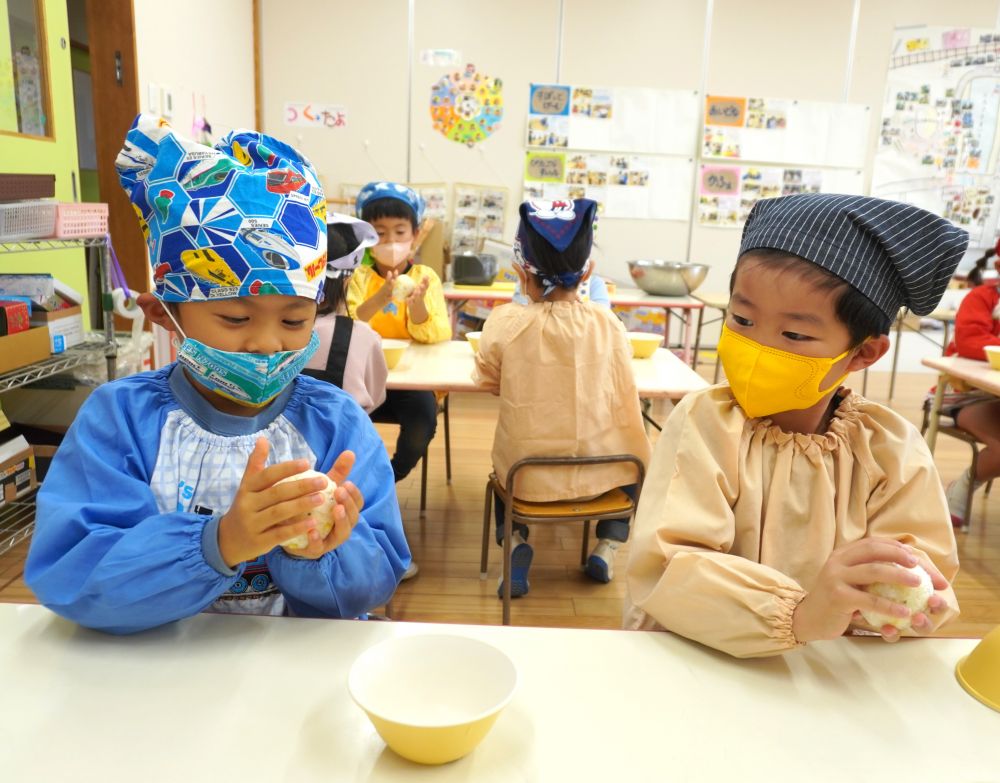お椀の中へほかほかのさつまいもご飯を入れ、ラップで覆います♡
ラップでご飯を包んだら、あとは好きな形ににぎにぎするだけ♪

「三角おにぎりに挑戦してみたい！」
「私はまんまるおにぎり！」と、思い思いの形へ。
「ボールみたいにきれいに出来た！」「上手じゃね」と、友達と見せ合いっこ♡

女の子に一番人気なのは“ハート♡のおにぎり”でした。
理想の形に近づけようと、指を使い試行錯誤。
可愛い仕上がりとなりますように・・♡
