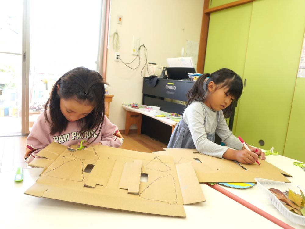 拾ったどんぐりや葉っぱなどの自然物を使って何がしたいかみんなで話し合い・・・
「ボーリングみたいなゲームがしたい！」
「ごちそうを作りたい！」「どんぐりごまも！」
「お店やさんをしてお客さんを呼びたい！」
よし、お店屋さんしよう！！！　協同遊びが始まりました♡



ケーキやアイスなどのデザートを作る『カフェグループ』
段ボールを土台にして作ることになりましたが…
固くて切るのが結構難しい！！