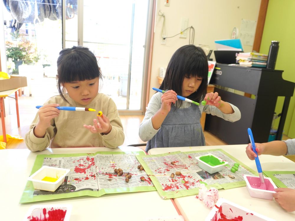 「いちごとかをどんぐりにする？」
「赤色に塗ったらいんじゃない？」
「どんぐりに色を塗ってフルーツにしよう！」
「キウイは黄緑で！」

ポスカやペンでは色がつきにくいことに気付き絵の具に変更しました☆