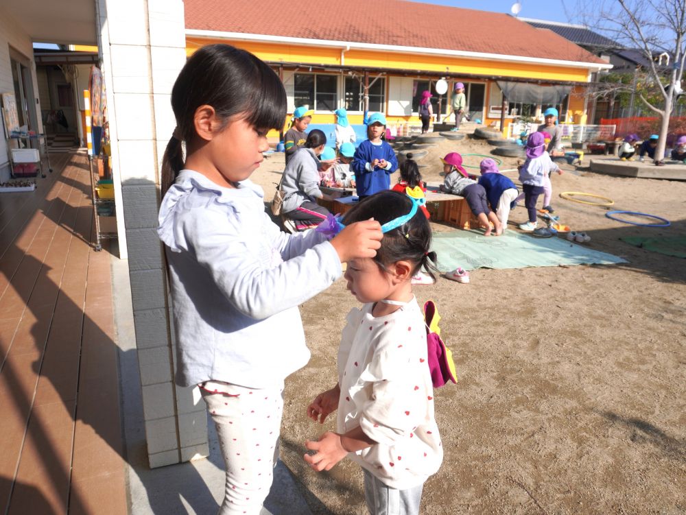 「Iちゃんちょっと来て～」
「小さいかな？ぴったり？」
「あーちょっと小さかったー」
実際に小さいクラスの子につけてみて調整をしました！
長さや大きさが正しくないことに気付き作り直します！