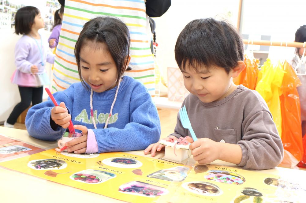 年長児と関わるなかで生まれるあこがれの気持ち♡
見て、真似て、経験しながらさまざまな学びが！



　「めっちゃうまそ～！！」
　「これ、どうやって作ったんかね！？」
本物のようなスイーツにワクワクが止まらない♡
一緒に頼んだり、見せ合いっこしたり…
カフェ気分を満喫♡