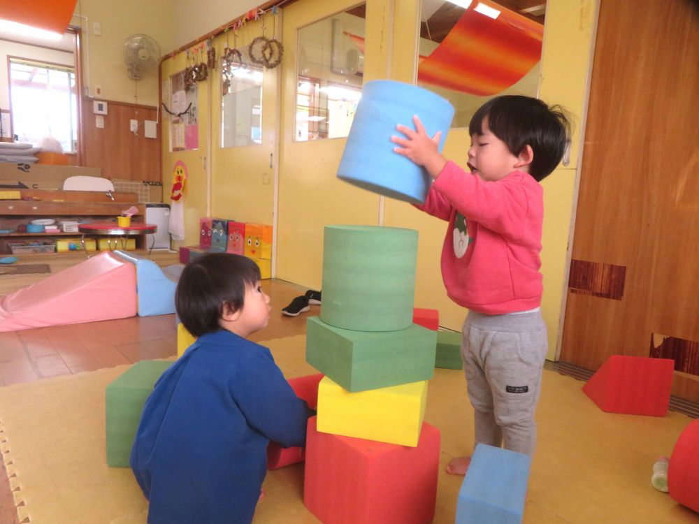 保育室に新しくソフトブロックが登場！
丸、三角、四角の形があり、軽くて運びやすいブロックです
興味をもち、さっそく遊び始めました！

「積み上げて高くしてみたい！」
同じ気持ちの友達同士、自然と意気投合し
二人で協力して積み上げていきます！

