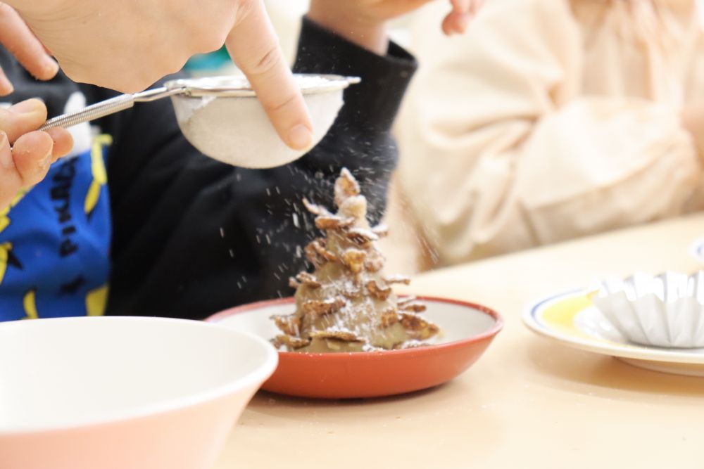 コーンフレークをさしたら最後に雪に見立てた粉砂糖をかけて完成です
白く色着く様子に子ども達のテンションも上がります