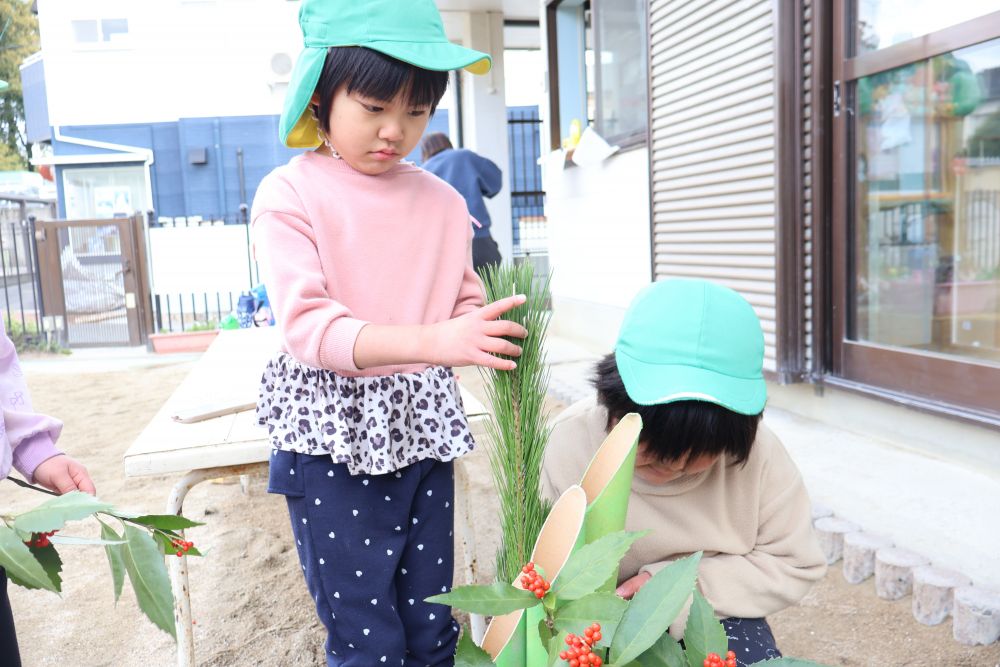 お休み前最後の登園日！
いつもよりも風の冷たさを肌に感じながら遊んでいたキリン組さん。

『お正月の飾りつけするよ～』
と声をかけると、
「一緒にしたーい！」
「何作るの～？」
興味津々✨

門松づくり開始～！！
葉牡丹を植えてくれたAちゃんとKちゃん。
「お花みたい！」
「かわいいね～」

松の葉っぱはちょっぴりチクチク・・・