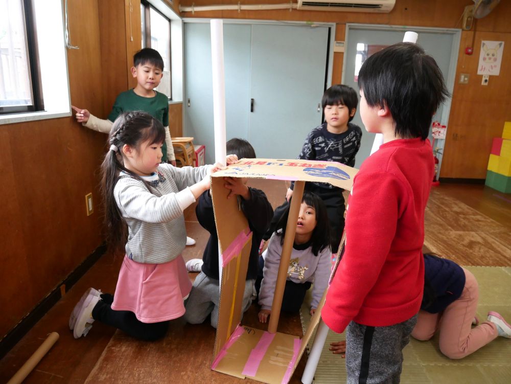 キャラクターが描いてある廃材を切って
映画館を楽しんでいた友達から始まり
今度は友達と協力して大きな映画館を作ることに

まずは大きな段ボールを切って
立たせたいんだ！！と試行錯誤
この段ボールを立たせるのに大苦戦…

長い棒を支えに立たせる作戦にしてみましたが
うまく立ちません
「じゃあ二本ずつに増やしてみよう」
「ここ持っとくよ」　「誰かくっつけて」
それでもグラグラしてうまくいきません…