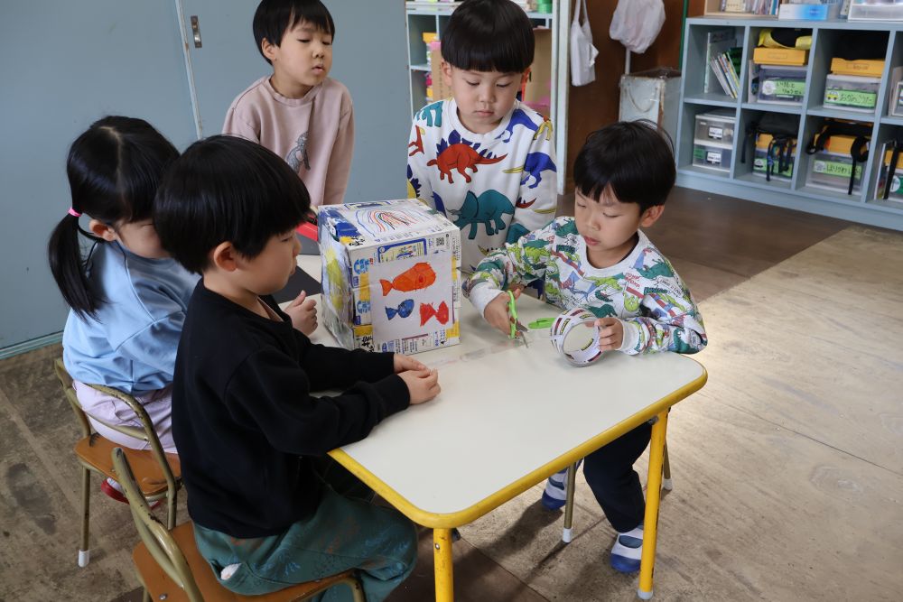 保育参加で見ていただいた所から
またさらに遊びが進んでいるゾウ組さん


【乗り物すごろく迷路】
みんな乗り物が完成し、サイコロ作りがスタート!(^^)!
一人ひとりが一枚ずつ絵を描いて貼り、
あと一面が残りました・・・
「どうする？」
とグループのみんなで話し合うと、
「みんなで虹をかきたい！！」と♡
自分たちでどうやって描くか決めて
一つの虹を完成させていました！！
「サイコロ転がるかやってみよう(^^♪」
と順番に試して、いい感じ👍と喜んでいましたよ！