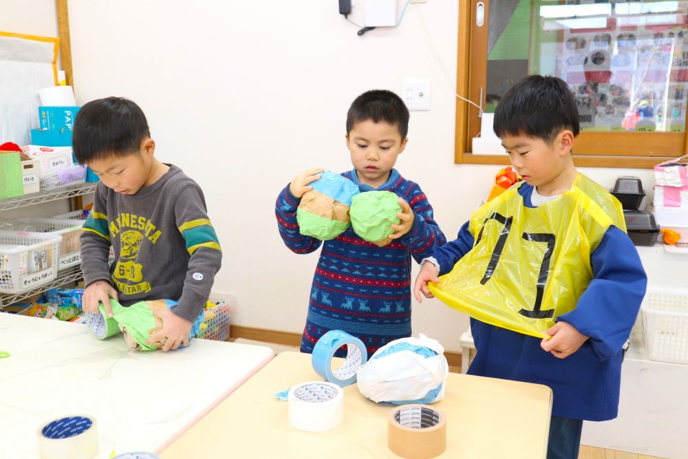 「本当のボールじゃ、段ボール壊れるかもしれんけみんなでボール作ろう」
「小さい子も遊びに来てくれるから、柔らかいほうが良いもんね！」
「広告なら、痛くなさそうじゃない？それ丸めてつくろう！」
相手のことも考えて作っていく姿

「意外と丸くするの難しいね・・」
「おさえてぎゅっとしてたらボールぽくできてきたかも！」
諦めずやってみる姿