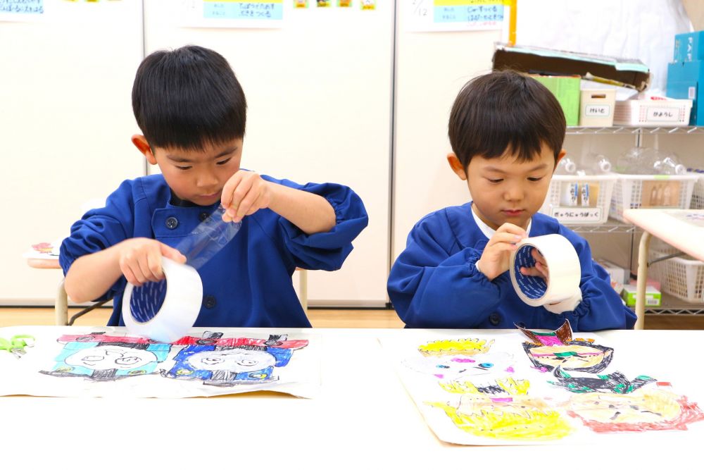 「ボールあったったら絵が破れんかね？」
「透明テープ貼るか、お絵描きの下敷きみたい(ラミネート)にするか・・・？」
「透明テープでも強いと思う！」
「ラミネートでもしてみる？」
「こっちとこっち、どっちもしてみるか！」

気になったらどちらも試してやってみて考えようとする姿も・・
透明テープを貼っていく・・
「これ意外と大変じゃん・・」
そう言葉にしながらも
友達が頑張っている姿を見て
最後までやり抜くHくんとSくん
